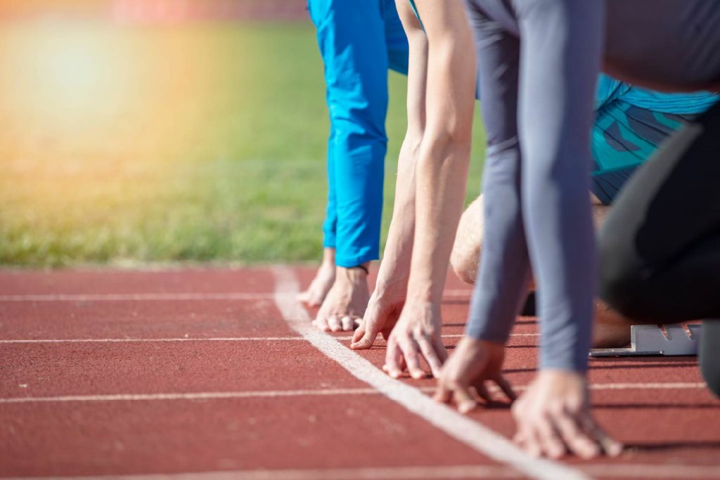 Close up of the hands of runners crouching down on the start line of a sprint race
